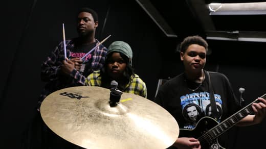 The band behind a crash cymbal, drummer holding sticks up